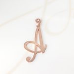 DIJE RECUBRIMIENTO DE ORO ROSA CURSIVA A LISO